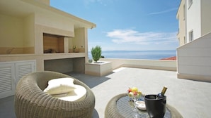 A balcony with wicker furniture, a small table with a drink, and a view of the sea. - Makarska Lux Apartments A4 (2+1) (Veliko Brdo, Makarska)