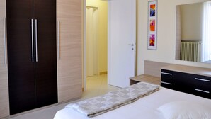 Une chambre à coucher comprenant un lit, une armoire, une porte donnant sur une autre pièce et un miroir avec un radiateur.
