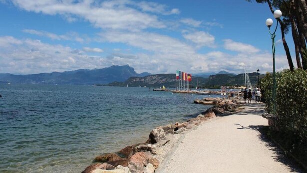Une promenade en bord de mer offrant une vue dégagée sur l’océan, le rivage rocheux et les montagnes lointaines.