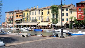 A waterfront area with boats docked, buildings with balconies, and a street lamp.