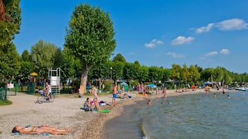 Une plage où l’on peut se détendre au soleil et se baigner, une aire de jeux et un grand arbre.