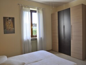 Une chambre à coucher avec un lit, une armoire et une fenêtre avec des rideaux.