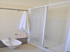Ein Badezimmer mit Dusche, Waschbecken und zwei Handtüchern.