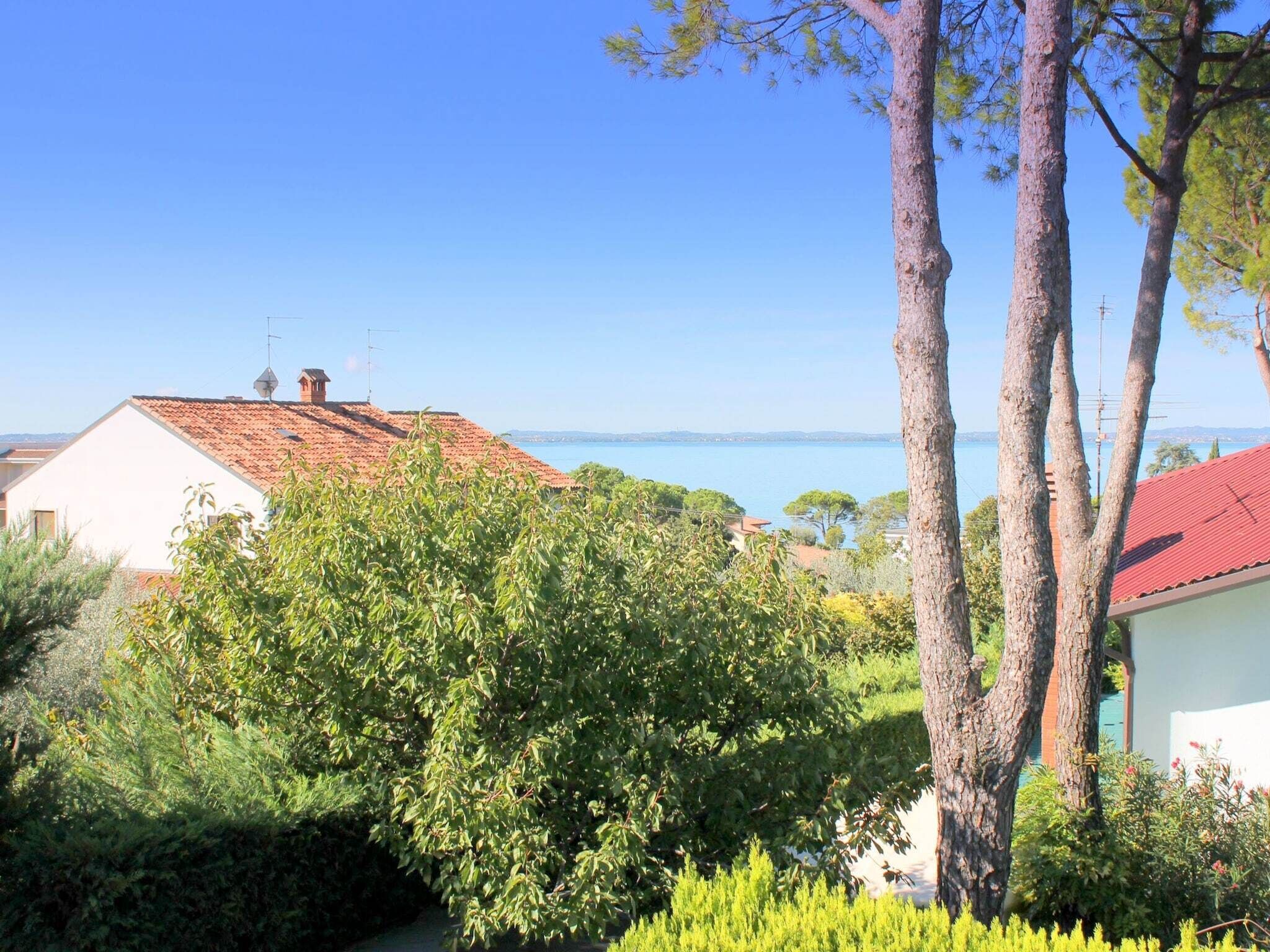 A coastal view with a house, trees, and a clear sky.