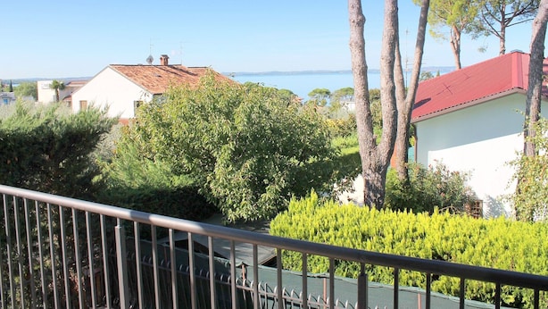 A residential area with houses, trees, and a clear view of the sea.