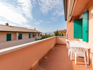 A balcony with a table and chairs, a view of neighboring buildings, and a clear sky. - Retreat at Via Toscanini (Lazise)