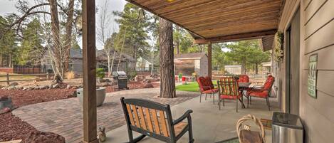 Un espacio de patio cubierto con un banco de madera, mobiliario exterior y un bote de basura.