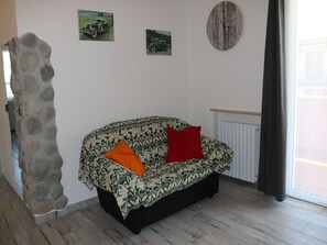 A living room with a patterned sofa, a stone wall, and two vintage car paintings on the wall.
