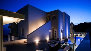 Ein moderner Poolbereich im Freien mit Liegestühlen und einer Treppe, die zu einer erhöhten Ebene führt.