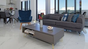 Un salon moderne avec un canapé gris, un fauteuil bleu et une table basse.