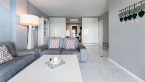 Un soggiorno moderno con un divano grigio, un tavolino bianco e una lampada.