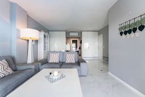 Een moderne woonkamer met een grijze bank, een witte salontafel en een lamp.