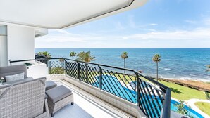 Un balcone con mobili da esterno, una piscina e vista sull'oceano.