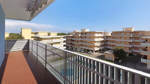 En balkon med gelænder, der kigger ud over et boligområde med høje bygninger.