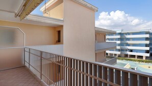 A balcony with a metal railing, a tiled floor, and a view of adjacent buildings. - Studio "Valbella A" in Residence with 12 Pools (Bibione)