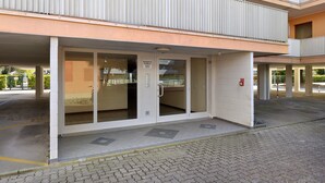 A building with a covered entrance, a sign indicating a parking area, and a fire alarm. - Studio "Valbella A" in Residence with 12 Pools (Bibione)