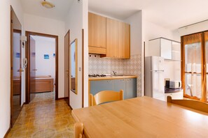 Une cuisine de taille réduite, dotée de meubles en bois, d’un four à micro-ondes et d’un évier.