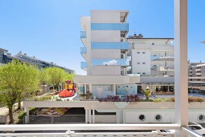 Un immeuble à plusieurs étages doté de balcons, d’une aire de jeux et d’un parking couvert.
