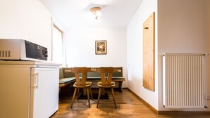 A compact kitchen with a microwave, a small refrigerator, wooden chairs, and a bench. - Apartment 'Issingerhof 1' with Mountain Views, Garden & Wi-Fi (Campo di Tures)