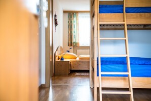 Un dormitorio con literas, un escritorio con lámpara y una ventana con cortinas.