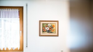 Una habitación con ventana, un cuadro con flores en la pared y un sofá estampado.