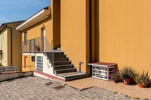 A building with a staircase, a small outdoor seating area, and potted plants.
