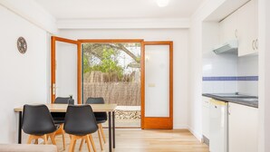 A modern kitchen with white cabinets, a built-in oven, and a dining area with a wooden table and black chairs.