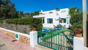A white building with a pool, green shutters, and a green gate.