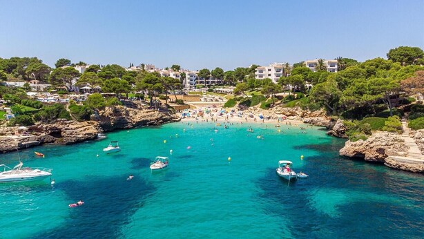 A coastal area with clear turquoise waters, boats, and a beach with people. - Apartment "Felipe 2-3" with Shared Pool, Wi-Fi & Terrace (Tourist Taxes Included) (Cala Dor)