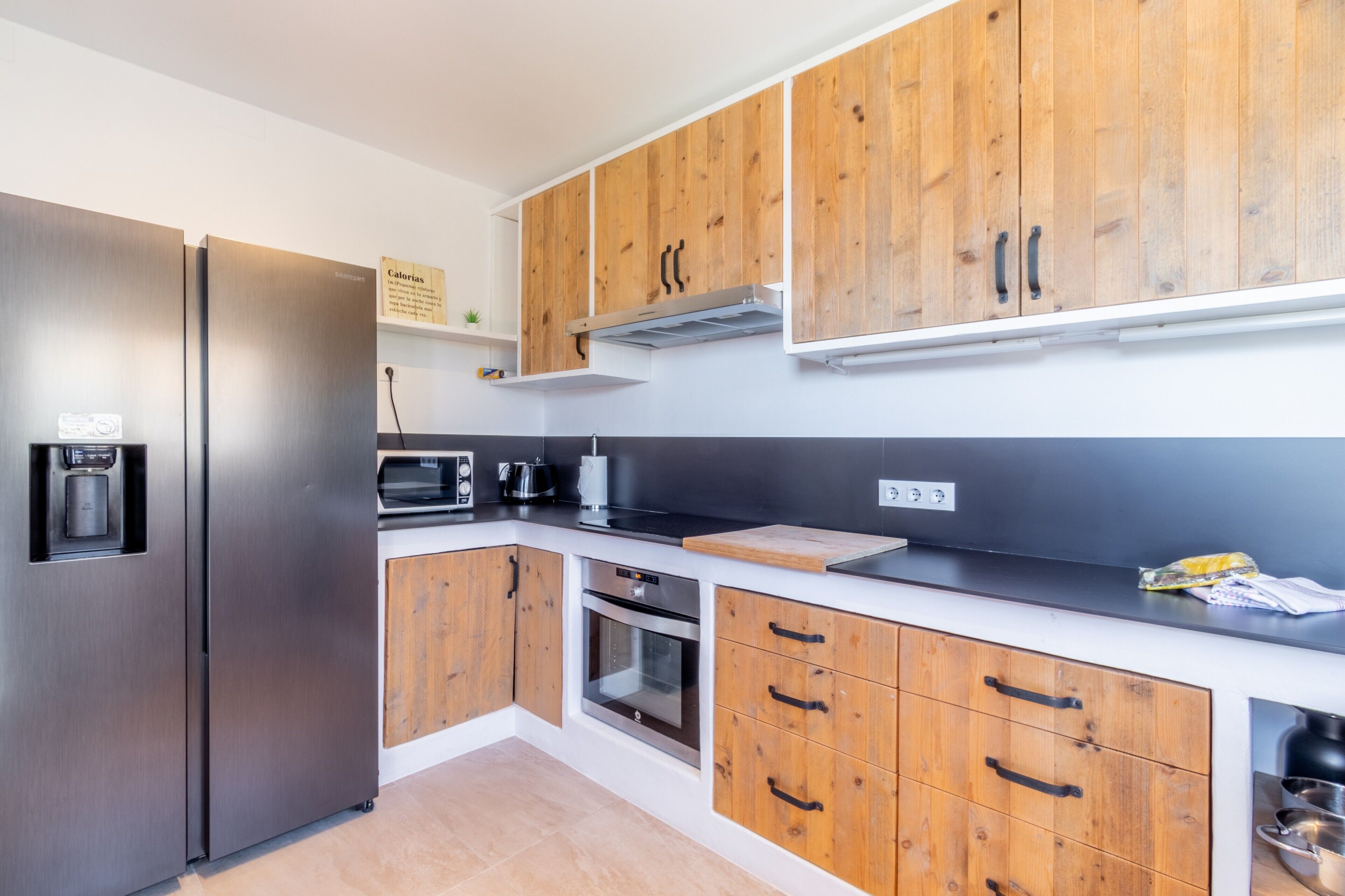 Een moderne keuken met roestvrijstalen apparatuur, houten kastjes en een zwart aanrecht.
