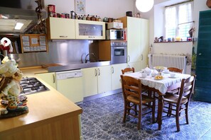 Una cucina con tavolo da pranzo, mobili, piano cottura e frigorifero.