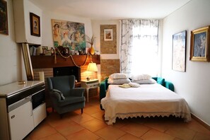 A bedroom with a bed, a chair, a desk, a fireplace, and artwork on the walls. - Holiday Home "Re Piano appartamento Le Rondini" with Lake View, Sauna & Wi-Fi (Modigliana)