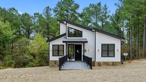 A two-story house with a stone foundation, a black front door, and a small porch with a railing.