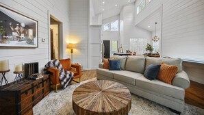 A spacious living room with a large sofa, a round wooden coffee table, and a fireplace.