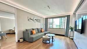 Ein modernes Wohnzimmer mit einem grauen Sofa, einem runden Couchtisch und einem großen Fenster.