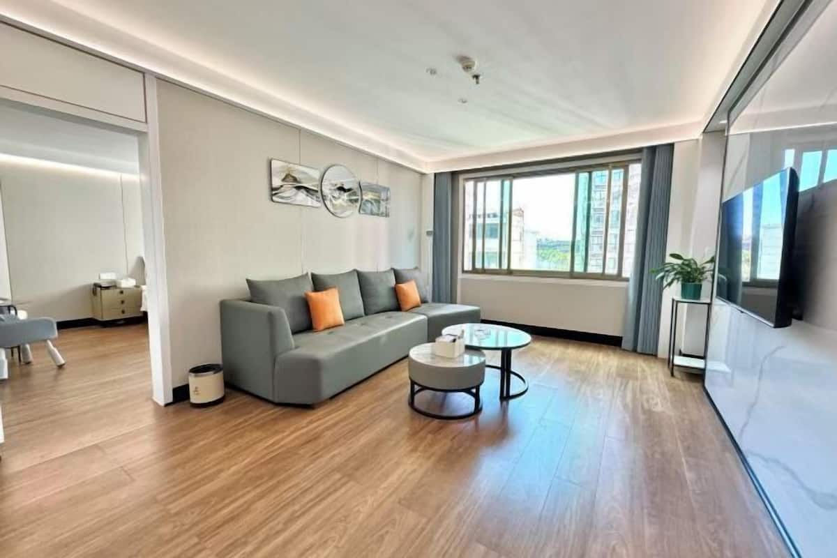 A modern living room with a grey sofa, a round coffee table, and a large window.