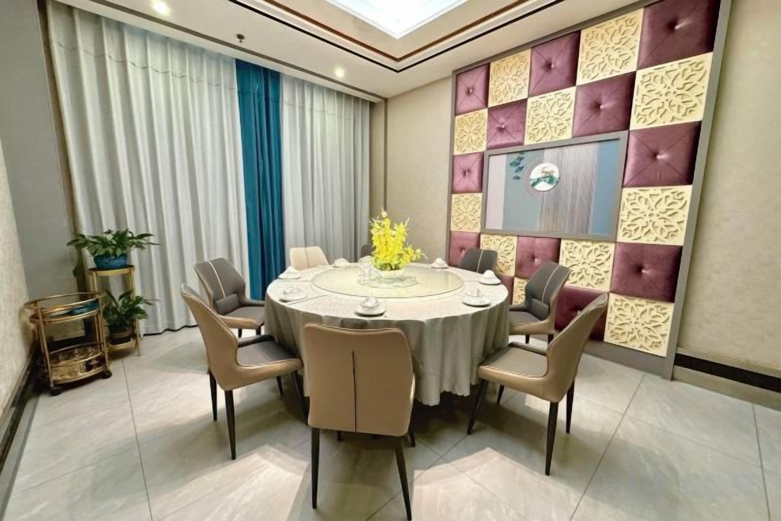 Une table de salle à manger ronde, entourée de chaises, agrémentée d’un élément décoratif central et adossée à un mur orné de panneaux à motifs.