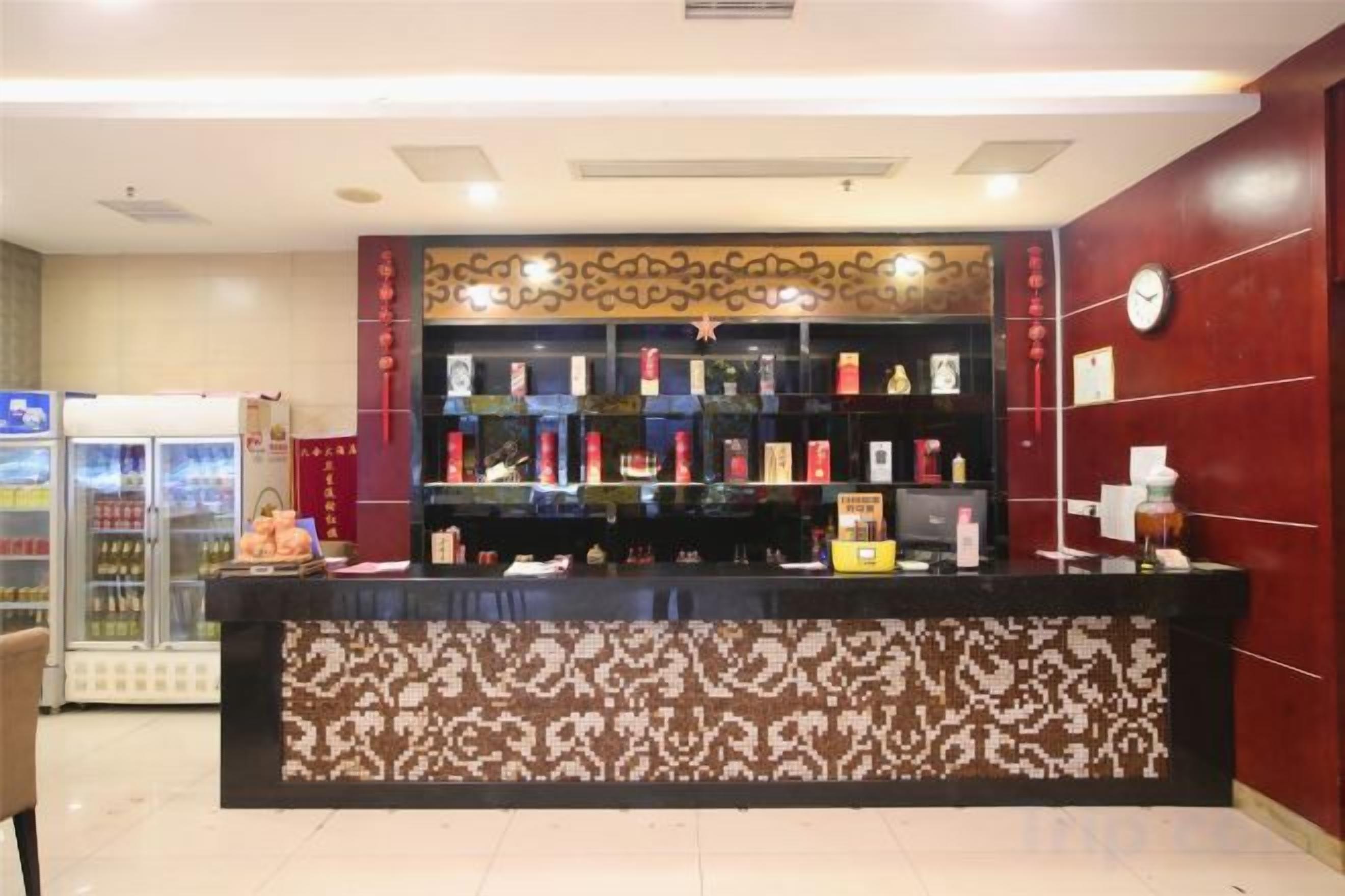 A reception desk with a patterned counter, a clock on the wall, and a refrigerator to the left.