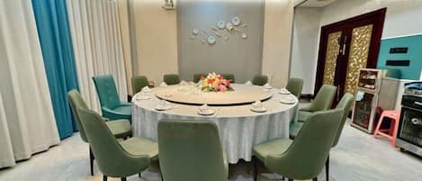 A round dining table with chairs, a floral centerpiece, and a modern ceiling design.
