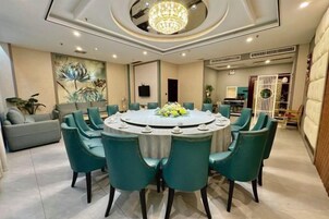 Uma sala de jantar com mesa redonda, várias cadeiras e um lustre.