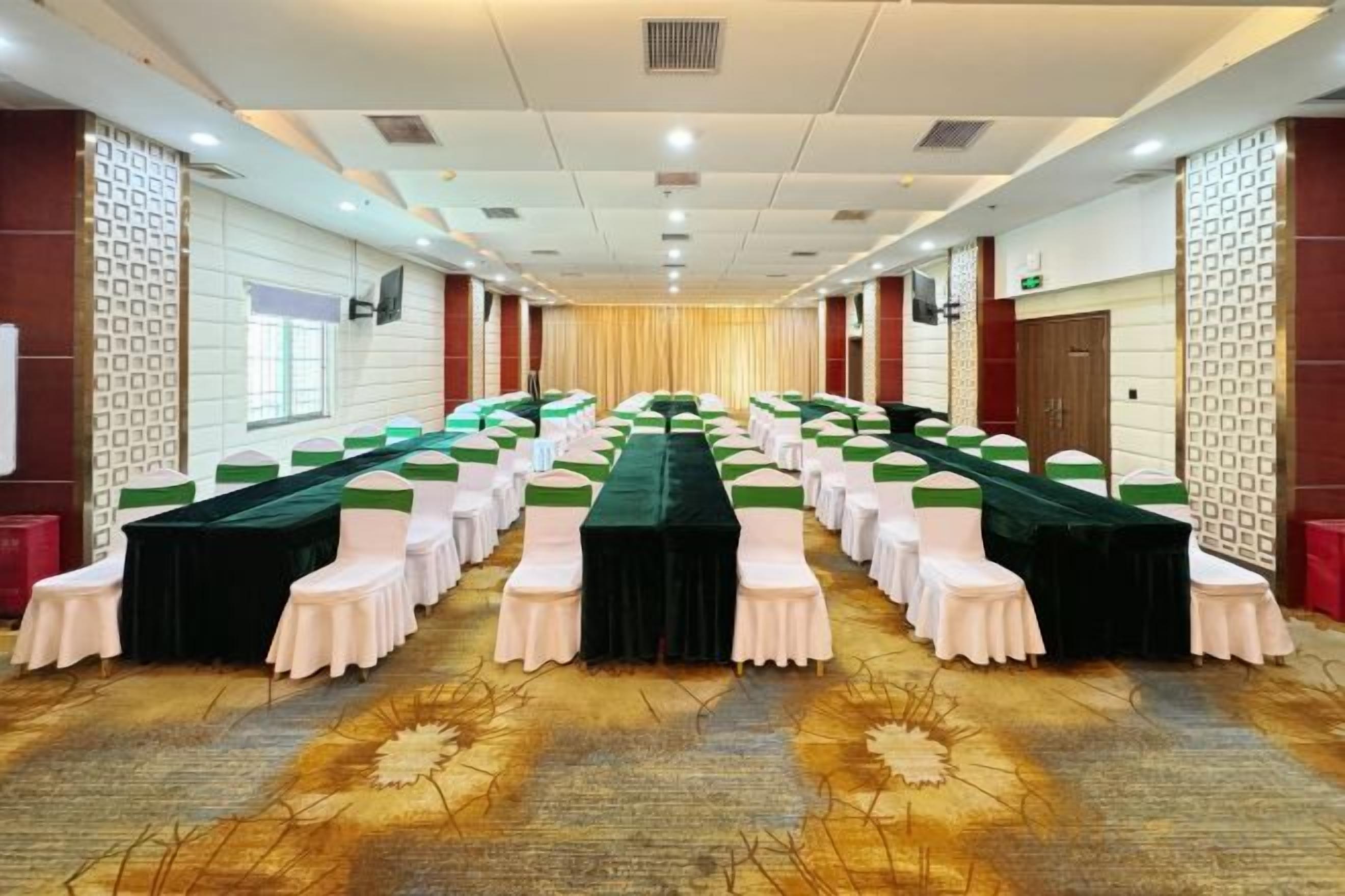A conference room with rows of tables, chairs, and a carpeted floor.