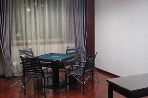 Una habitación con mesa de billar, cuatro sillas, una mesita y una ventana con cortinas.