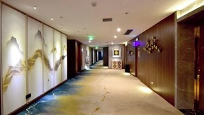 Ein Hotelkorridor mit langer, schmaler Gestaltung, an einer Seite mit einem Wandmuster und an der anderen mit Holzvertäfelung.