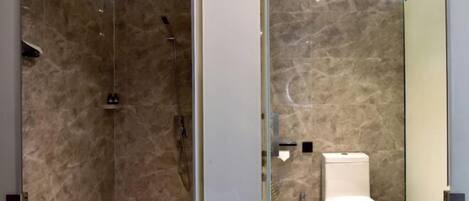 A modern bathroom with a glass shower enclosure, a toilet, and a marble-tiled wall.
