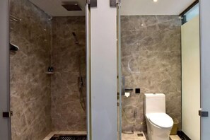 A modern bathroom with a glass shower enclosure, a toilet, and a marble-tiled wall. - Liuhe Hotel (Hengyang)