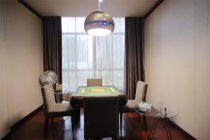 A room with a table, chairs, a fan, and a window with curtains. - Liuhe Hotel (Hengyang)