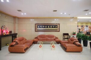 A lobby with a sofa set, a framed sign, and a small table with plants.