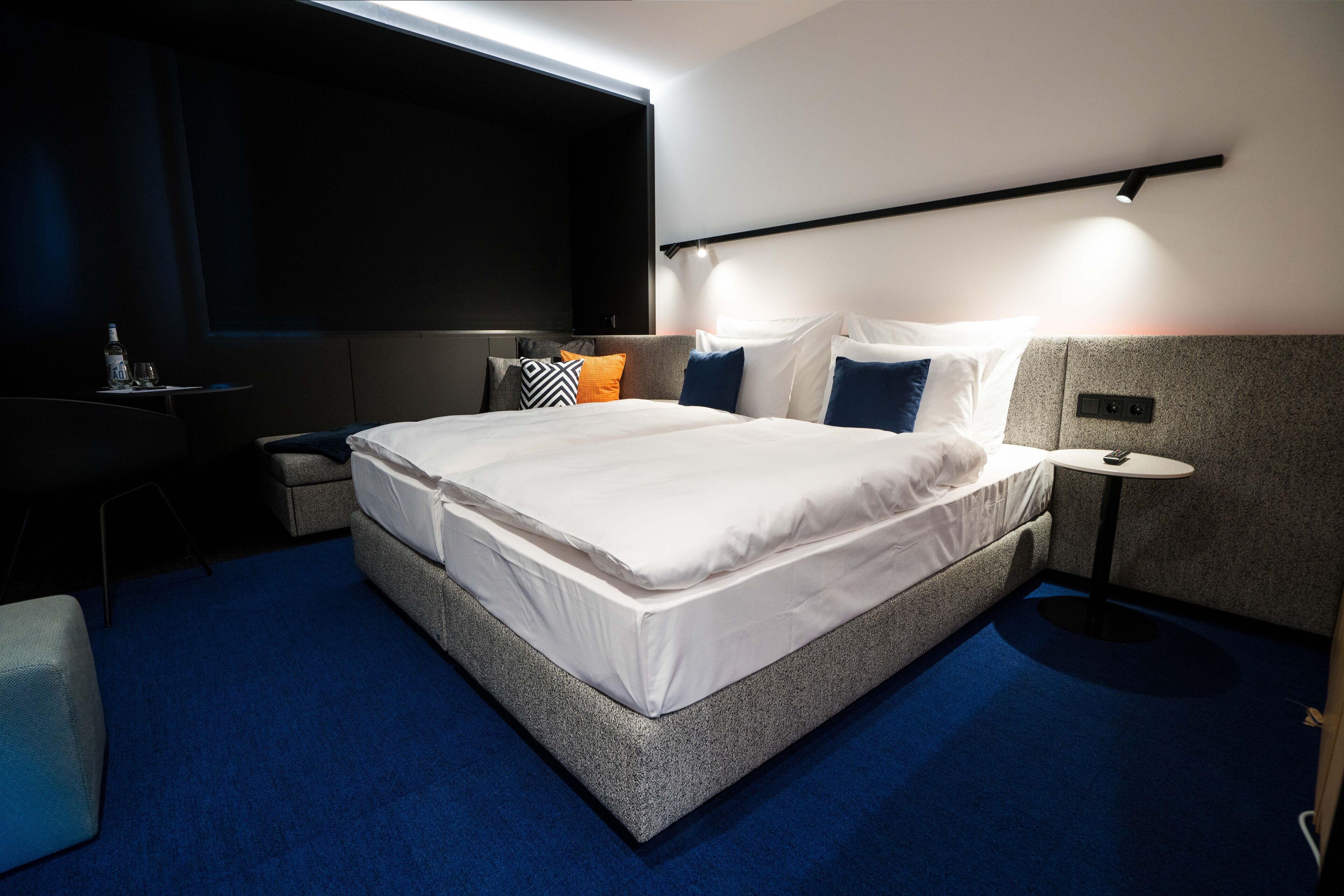 Een moderne hotelkamer met een groot bed, een klein tafeltje, een televisie en een zithoek.