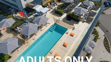 An aerial view of an adults-only resort with a swimming pool, lounge areas, and outdoor seating.