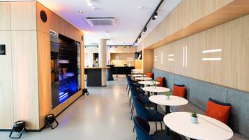 Un restaurant moderne avec des boiseries, des tables rondes et des chaises bleues.